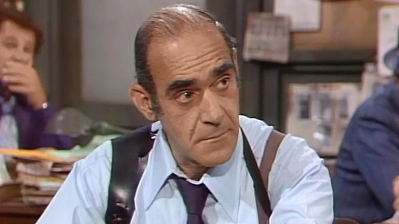 Abe Vigoda as Sergeant Philip K. Fish sitting at his office on Barney Miller