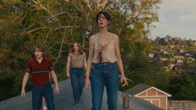 Anne Hathaway as Denise Platt with Christian Convery as Brian Platt and  Maisy Stella as Audrey Platt standing behind her on the roof in The End of Oak Strett