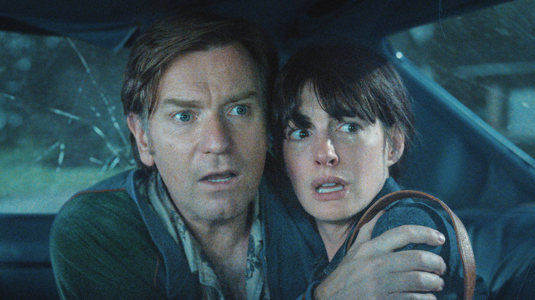 Ewan McGregor as Greg Platt and Anne Hathaway as Denise huddled together looking scared in The End of Oak Street