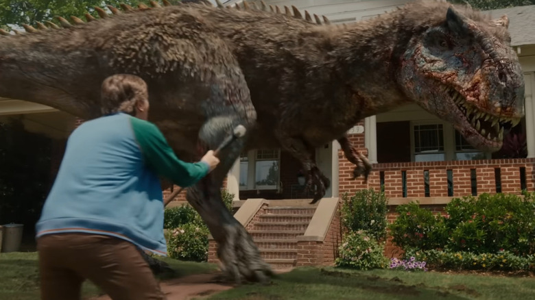 Ewan McGregor as Greg Platt getting ready to fighht a allosaur with a hammer in The End of Oak Street