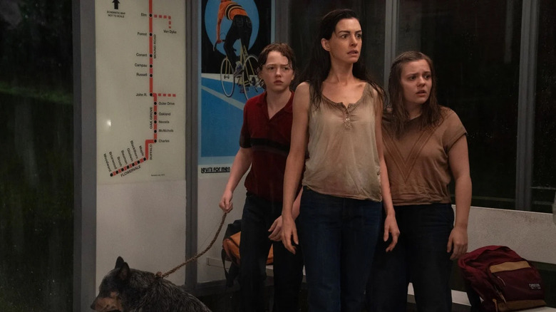 Denise (Anne Hathaway), Brian (Christian Convery), and Audrey (Maisy Stella) and Starbuck the dog wait at a bus stop in The End of Oak Street