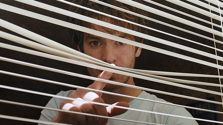 Andrew Garfield looking through the blinds in Under the Silver Lake