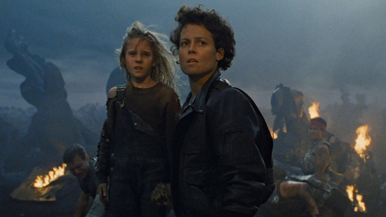 Sigourney Weaver as Ellen Ripley stands next to Carrie Henn as Newt in Aliens