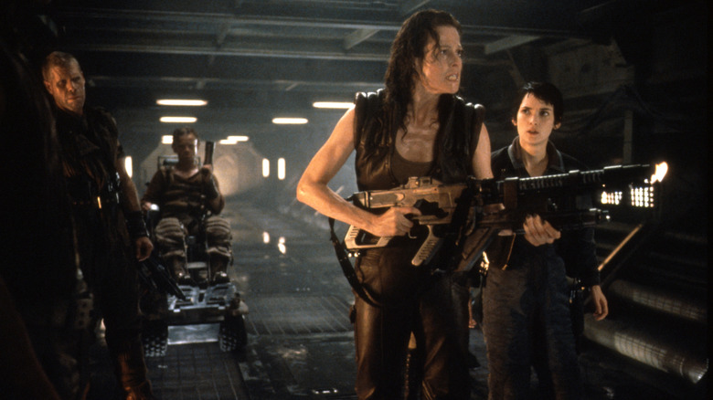 Sigourney Weaver as Ripley 8 holds a big gun in a tunnel with Call (Winona Ryder) and Johner (Ron Perlman) Alien Resurrection