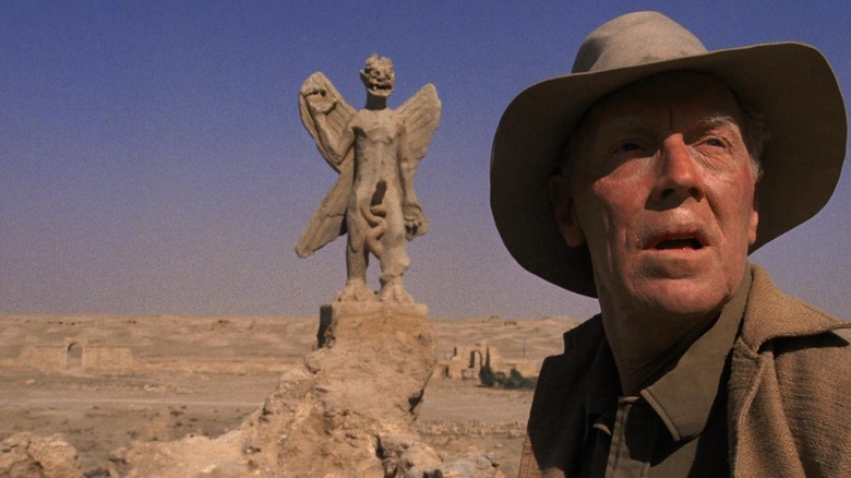 Father Merrin looking away from a statue of a demon in The Exorcist.