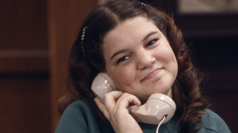 Mindy Cohn as Natalie Green, smiling on a phone call on "The Facts of Life"
