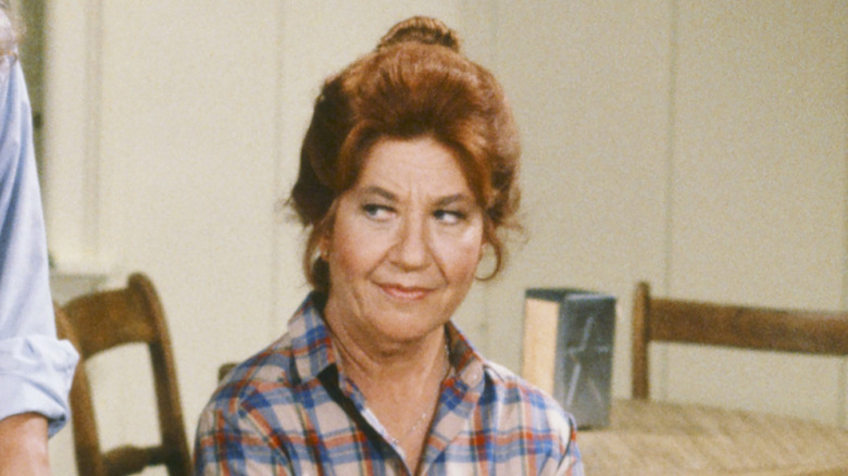 Charlotte Rae as Edna Garrett, smiling and sitting at a table on "The Facts of Life"