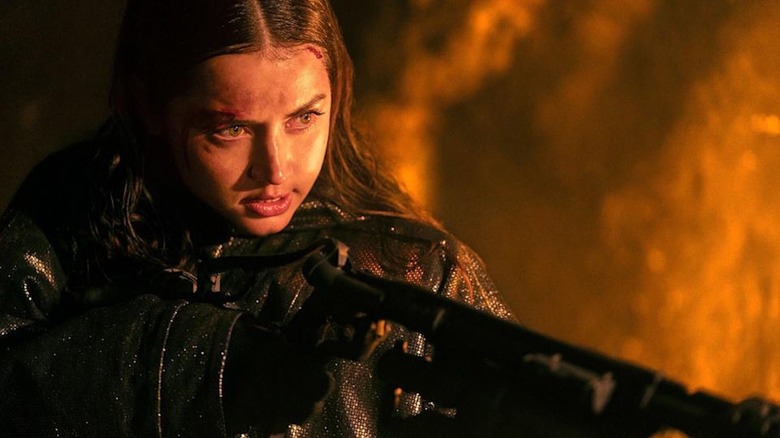 A bruised and bloodied Ana de Armas wields a flamethrower as Eve Macarro in Ballerina