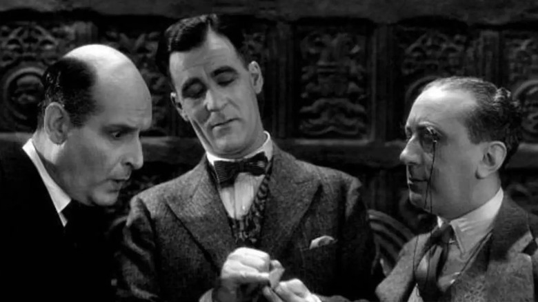 Poirot between two incredulous lookers-on in the film Alibi.