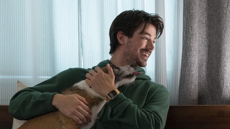 Grant Gustin as Max Stevenson, smiling and holding a dog in Puppy Love