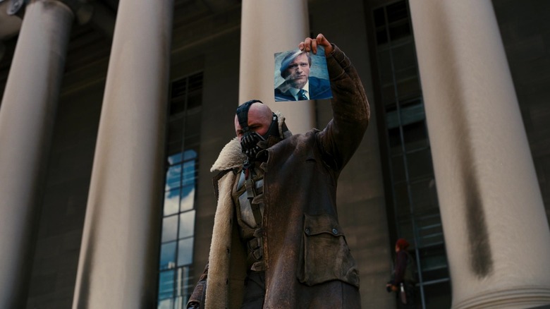 Tom Hardy as Bane wearing a leather mask and jacket featuring Harvey Dent from the film 