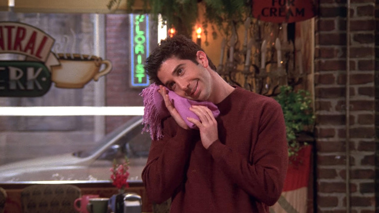 Ross Geller (David Schwimmer) stands in Central Perk while resting his head on a purple cloth in "Friends"