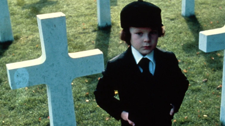 Damien Thorn in The Omen standing in graveyard