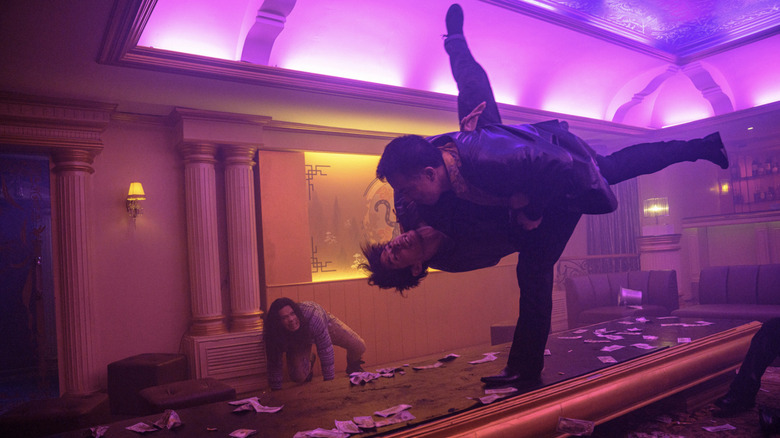 Navin body-slams a guy in a neon-lit room in The Furious
