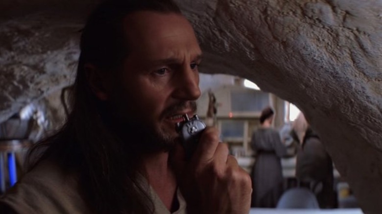 Liam Neeson as Qui-Gon Jinn speaks into his communicator