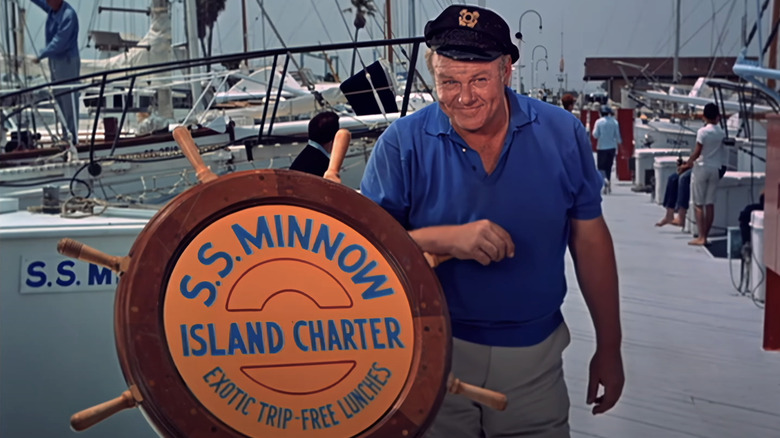 Alan Hale Jr.'s Captain Jonas Grumby stands next to the wheel named SS Minnow on Gilligan's Island