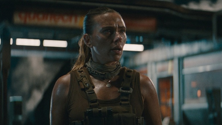 Scarlett Johansson as Zora Bennett standing in front of the gas station in Jurassic World Rebirth