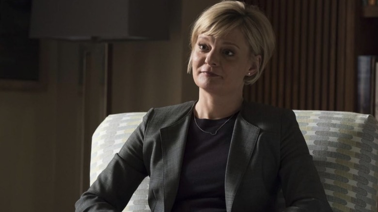 Martha Plimpton estava sentada em uma cadeira usando um terno