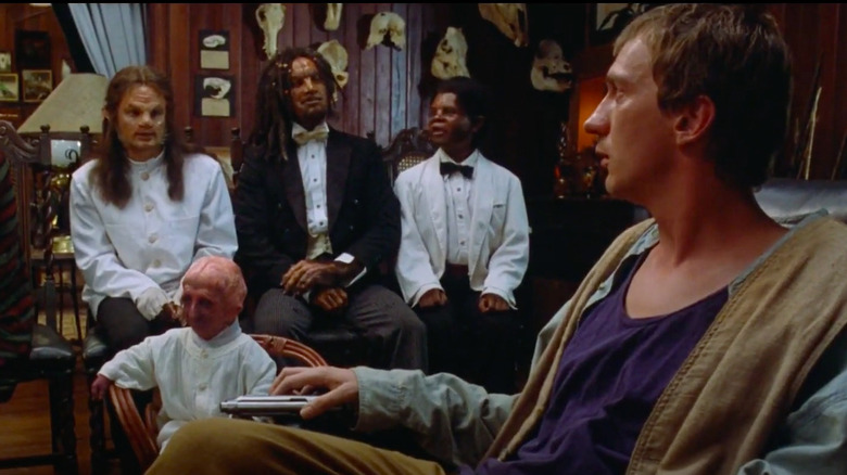 David Thewlis seated and staring at mutant men