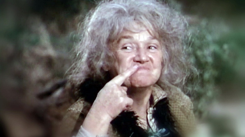 Dirty Sally pointing to her mouth and smiling in an episode of Gunsmoke