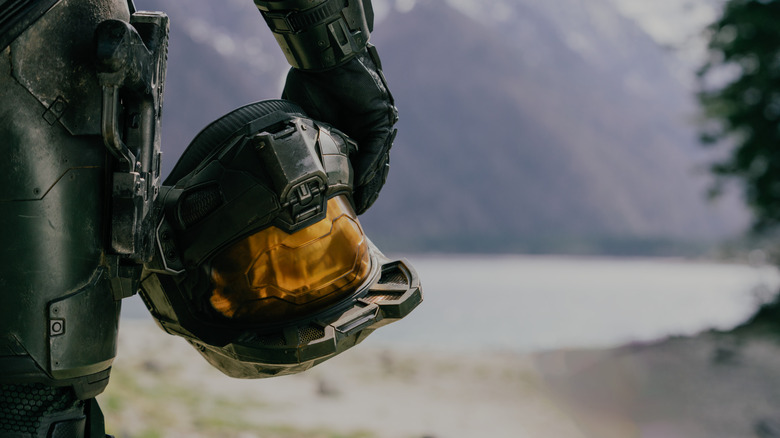 A close-up shot of Pablo Schreiber as Master Chief holding his helmet in his hand in Halo