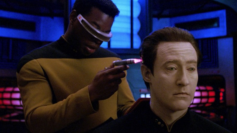 Geordi holding a glowing wand up to Data's brain on Star Trek: The Next Generation