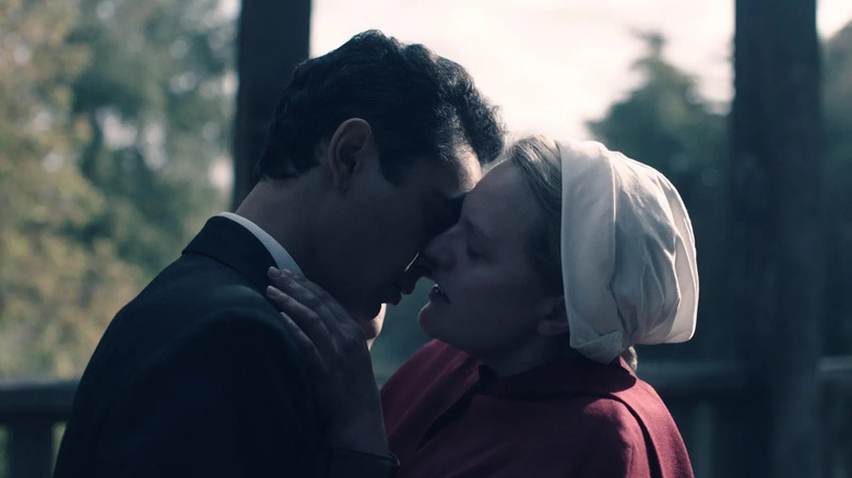 Juni (Elisabeth Moss), mengenakan jubah pelayan merah dan topi putihnya, memiliki wajahnya dekat dengan Nick (Max Minghella), hampir berciuman, dalam sebuah adegan dari 