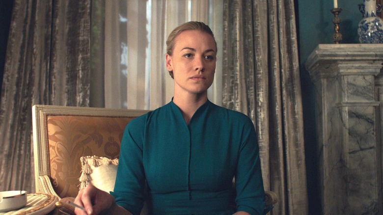 Serena (Yvonne Strahovski) with a solemn and focused expression, wearing the conservative teal dress for wives in The Handmaid's Tale