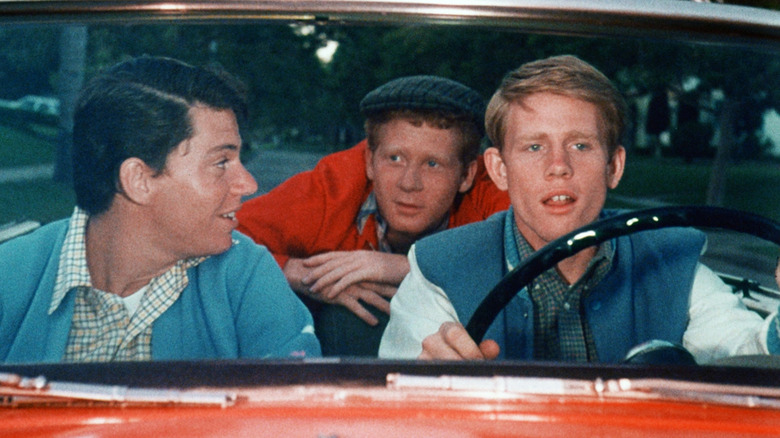 Richie Cunningham (Ron Howard) driving in a car with Potsie (Anson Williams) and Ralph (Don Most) on Happy Days