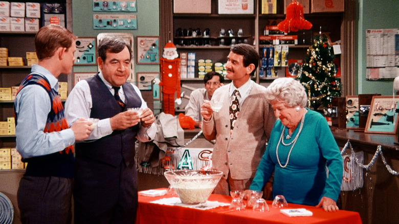 Richie (Ron Howard), his dad (Tom Bosley), and several others around a table drinking punch at a Christmas Party on Happy Days.