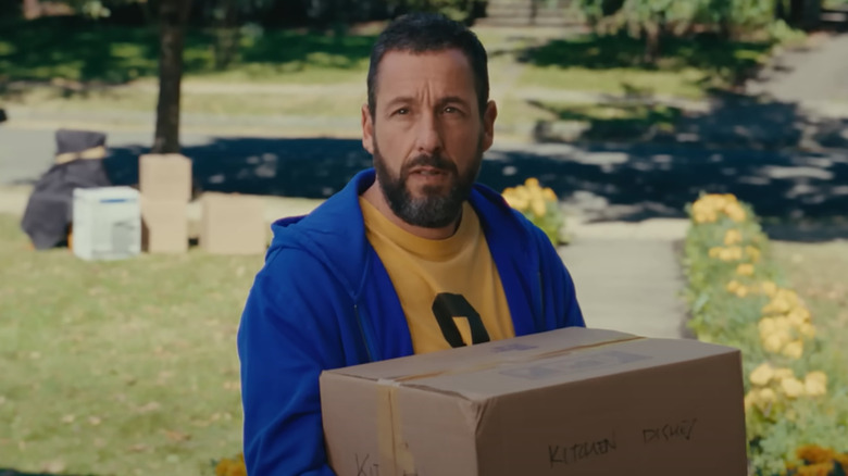 Adam Sandler as Happy holds a moving box as he looks wistfully at his grandmother's house in Happy Gilmore 2