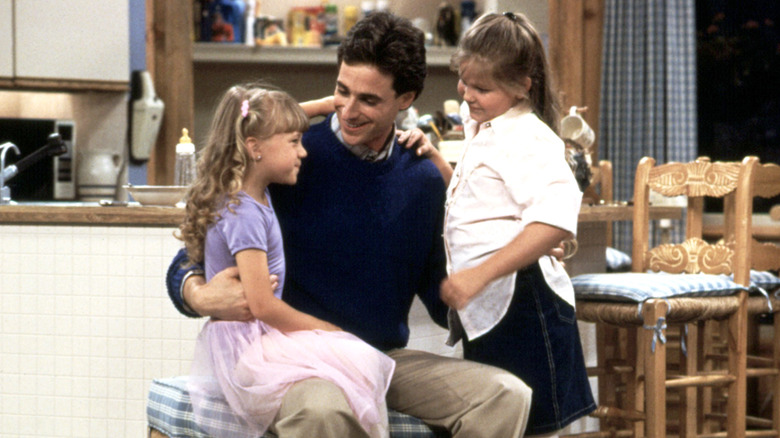 a man smiling at a little girl sitting in his lap with an older girl on his left side