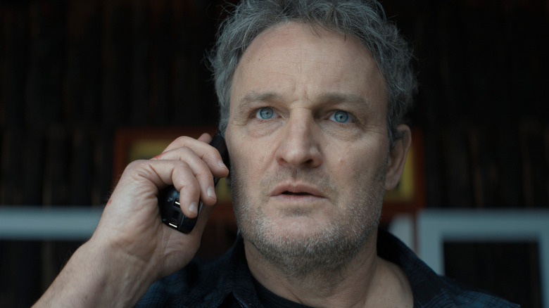 Jason Clarke as Frank Remnick taking a phone call with a concerned expression on his face in The Last Frontier