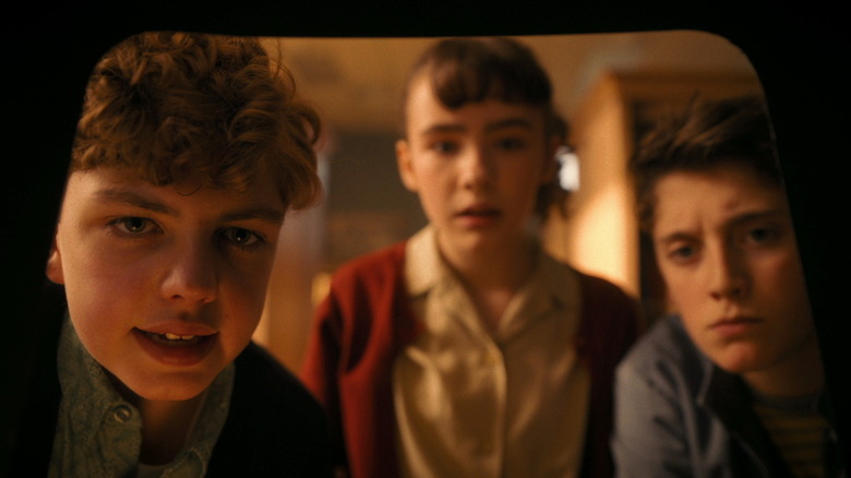 Mikkal Karim-Fidler's Teddy, Clara Stack's Lilly, Jack Molloy Legault's Phil look closely at something off camera in It: Welcome to Derry