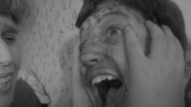 A man screams with injuries on his face in The War Game