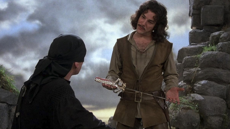 Inigo Montoya holds a sword in front of a seated Man in Black in The Princess Bride