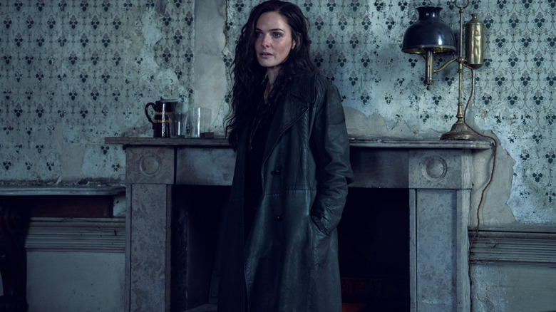 Rebecca Ferguson as Kaulo standing by a fireplace in a darkly-lit room in Peaky Blinders: The Immortal Man