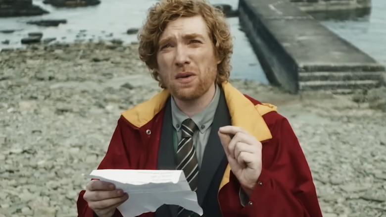Domhnall Gleeson as Daniel, reading a government memo on a beach in The Incomer