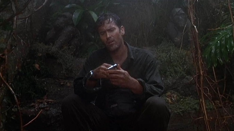 Bruce Campbell as Charlie Travis staring at an electronic device in Cogno