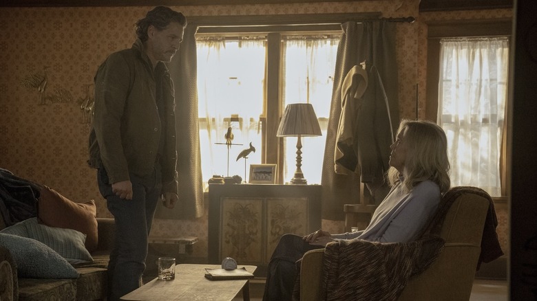 Joel standing and looking at a seated Gail in her house on The Last of Us