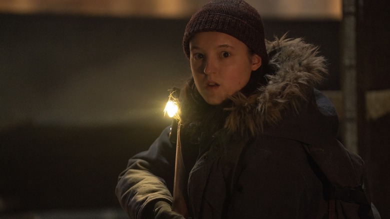 Bella Ramsey as Ellie holding a weapon and looking scared in The Last of Us