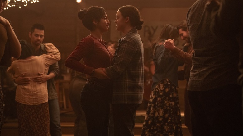 Bella Ramsey as Ellie and Isabela Merced as Dina sharing a romantic embrace at a dance in The Last of Us