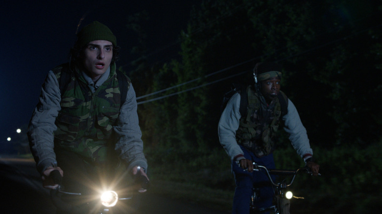 Mike and Lucas ride their bikes while wearing camo in Stranger Things