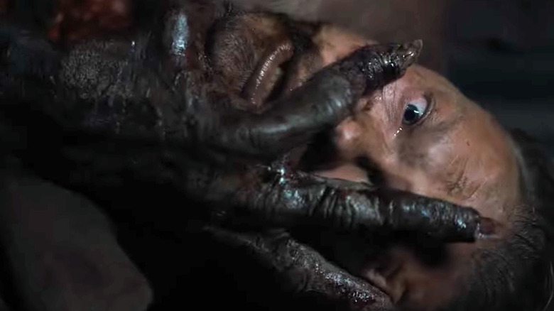 A clawed hand on a man's face