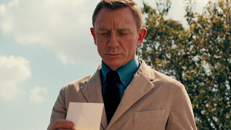 Daniel Craig looking at a card as James Bond in No Time to Die