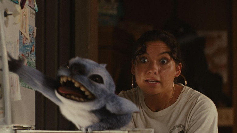Stitch grabs onto the fridge while Nani looks annoyed in Lilo & Stitch