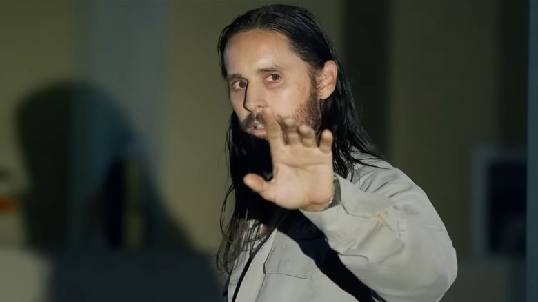 Jared Leto as Sparma holds up his hand to the glare of headlights, in The Little Things