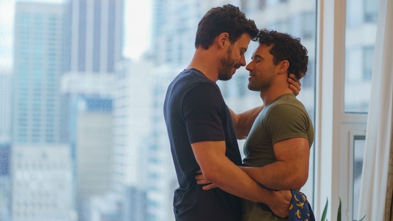 Scott and Kip embracing in front of a window on Heated Rivalry