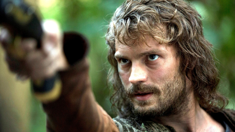 న్యూ వరల్డ్స్‌లోని అడవిలో పొడవాటి జుట్టు మరియు గడ్డంతో అబే గోఫ్‌గా జామీ డోర్నన్ తన చేతిని పట్టుకుని ఉన్నాడు