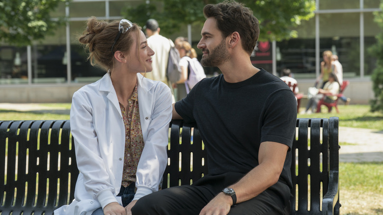 Olive and Adam smiling at each other on a bench in The Love Hypothesis